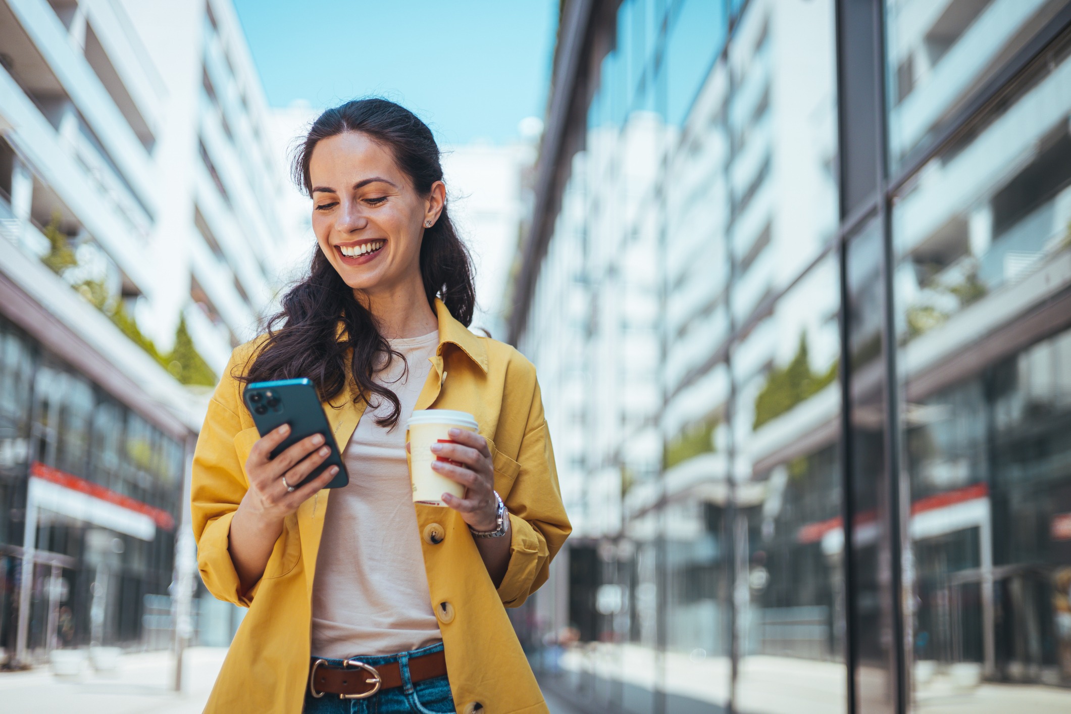 Woman walking on the sidewalk at urban setting and talking on the phone